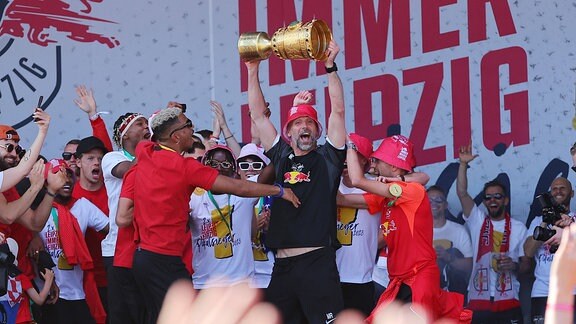 Die Mannschaft von RB Leipzig, DFB Pokalsieger 2023, feiert mit den Fans. Trainer Marco Rose hebt den Pokal in die Höhe.