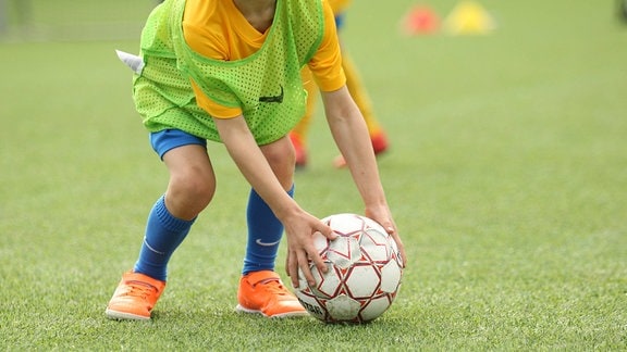 Ein Kind legt sich einen Fußball zurecht.
