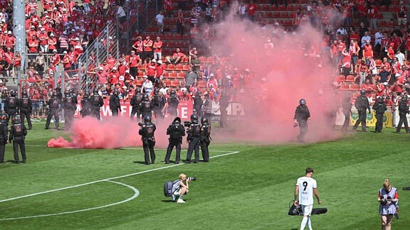 Eine rote Rauchbombe liegt vor der Fankruve vom FC Energie Cottbus