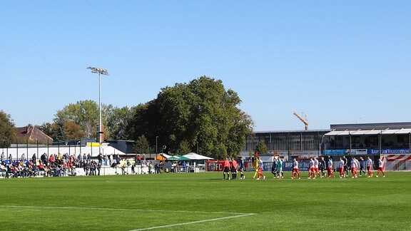 Eine Fußballmannschaft läuft auf einen Platz.