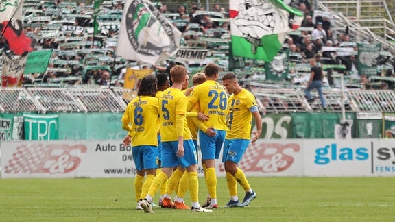 Die Mannschaft des 1. FC Lok bejubelt sein Tor zur 1:0-Führung. Im Hintergrund der Fan-Block der BSG Chemie.