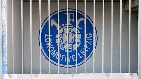 Emblem von 1. FC Lokomotive Leipzig hinter einem verschlossenen Tor