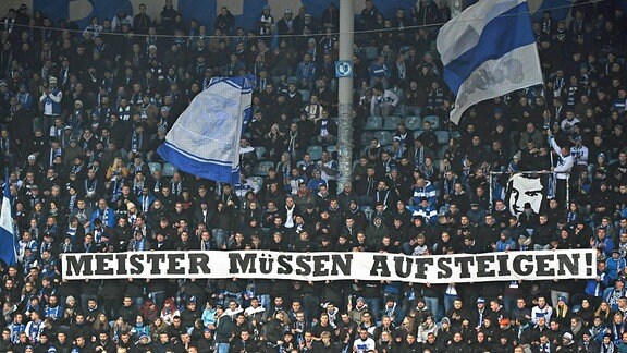 Fans des 1. FC Magdeburg kritisieren die Aufstiegsregelung des DFB in den Regionalligen mit "Meister müssen aufsteigen"-Transparent