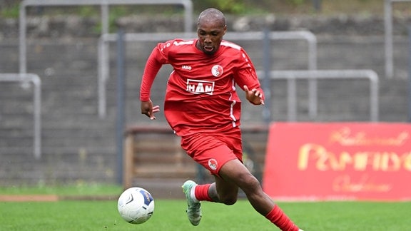 Ein Fußballspieler schaut in schnellem Lauf auf den Ball.