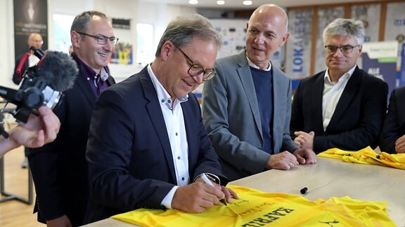 Hermann Winkler (DFB-Vize-Präsident, Präsident des SFV und NOFV) signiert ein Lok-Trikot mit Meisterstern.