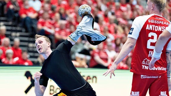 Handballspieler Omar Ingi Magnusson (SC Magdeburg) wirft den Ball energisch aufs Tor und hat dabei sein Trikot am Arm hängen.