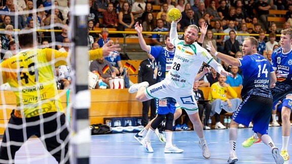 Maciej Gebala (Nr.28 , SC DHfK Leipzig) gegen Paul Skorupa (Nr. 14, VfL Luebeck-Schwartau) und Torhueter Nils Conrad (Nr. 49, VfL Luebeck-Schwartau). 