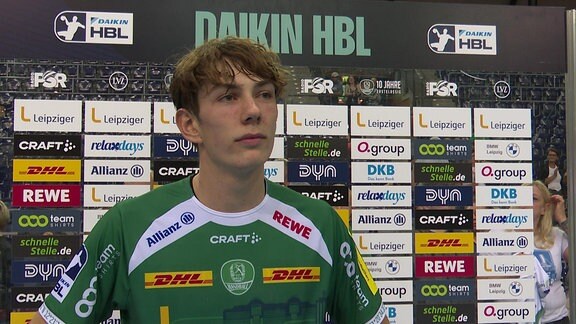 Handballspieler im Interview vor einer Werbebande