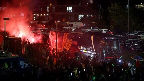 Der Mannschaftsbus des SC Magdeburg wird bei seiner Ankunft in Magdeburg von brennender Pyrotechnik beleuchtet.