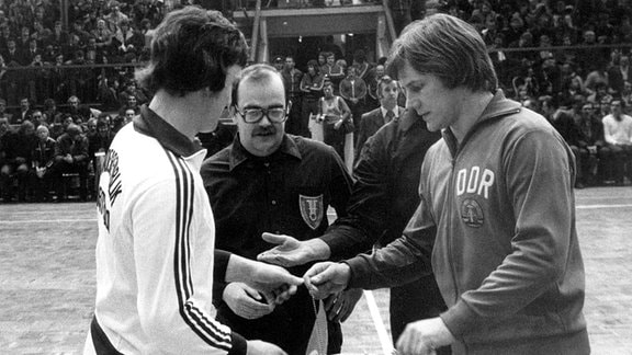 DDR-Spieler Wolfgang Lakenmacher (r) und BRD-Spielführer Horst Spengler (l) vor dem schwedischen Schiedsrichter Leif Olsson (M)
