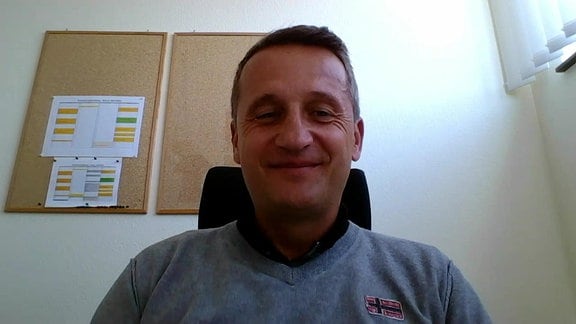 HFC-Sportdirektor Thomas Sobotzik vor einer Wand mit Korktafeln, grinsend