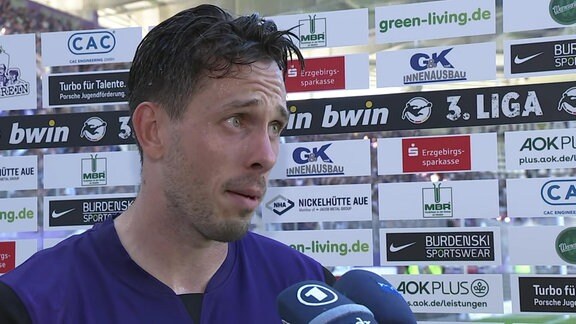 Aue-Stürmer Marcel Bär im Interview vor einer Werbetafel im Stadion