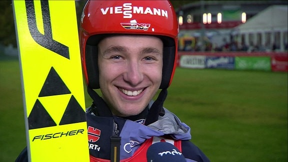 Skispringer Martin Hamann mit Skiern und Helm im Interview