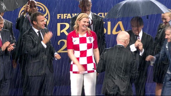 Kroatiens Staatspräsidentin Kolinda Grabar-Kitarovic (mi.) gemeinsam mit dem französischen Präsidenten Emmanuel Macron (li.) und weiteren FIFA-Offiziellen während der Siegerehrung nach dem WM-Finale in Moskau