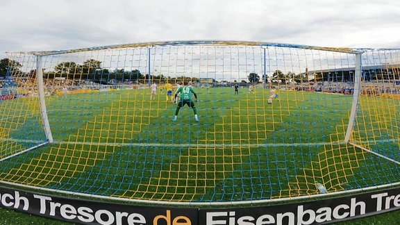 Blick durch das Netz eines Fussballtores auf das Spielfeld.