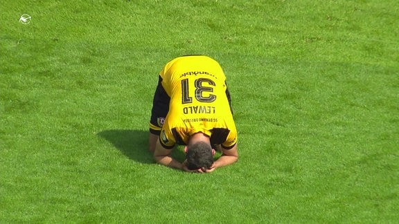 Ein Spieler von Dynamo dresden hockt auf dem Rasen.