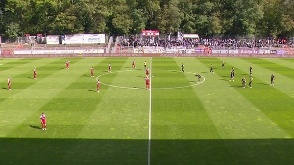 Mannschaften beim Anpfiff auf dem Spielfeld.