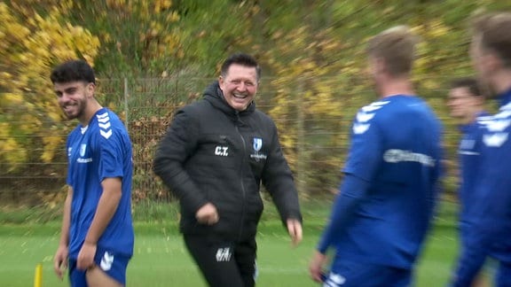 Trainer Christian Titz (m.) lacht im Kreis seiner Spieler.