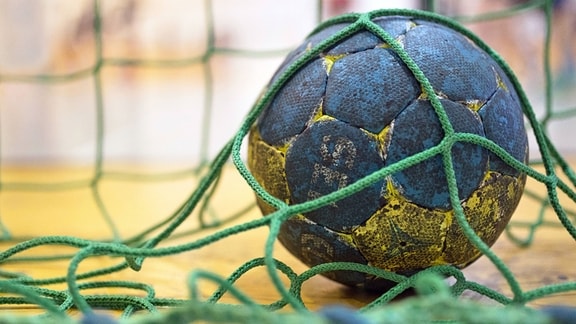 Ein Handball liegt im Netz eines Handballtors.
