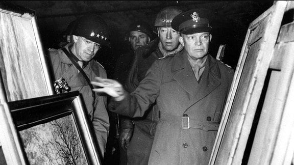 General Dwight David Eisenhower inspiziert mit General Omar Nelson Bradley und General George Smith Patton, jr. die von Nazis gestohlenen Gemälde im Bergwerk Merkers.