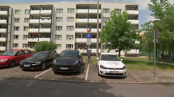 Fahrzeuge und Ladestation vor einem Plattenbau in Jena-Lobeda.