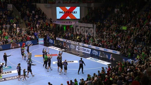 Nach einem Handballspiel stehen die Spieler auf dem Feld.