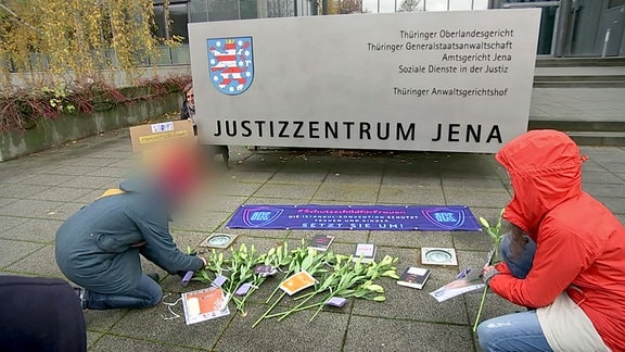 Weiße Lilien werden als Zeichen gegen Gewalt vor dem Justizzentrum Jena niedergelegt.