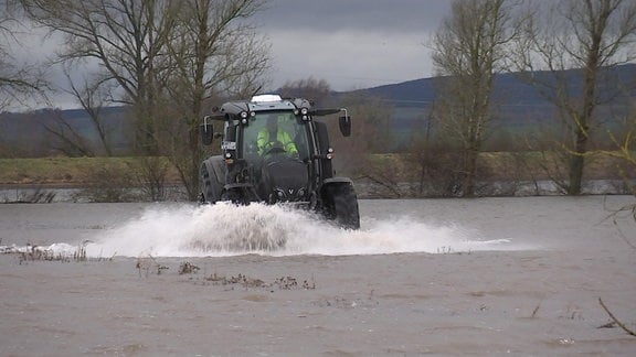 Traktor fährt über überflutetes Feld