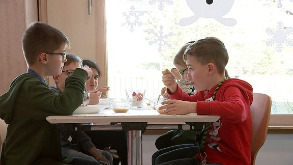 Kinder essen an einem Tisch