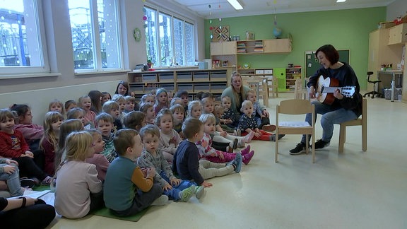 Manuela Müller, Kindergarten "Blauer Vogel" Rauenstein, mit einer Gitarre vor Kita-Kindern