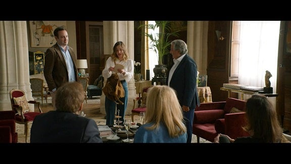Szene aus dem Film mit sechs Menschen, die in einem Raum eines Schlosses diskutieren 