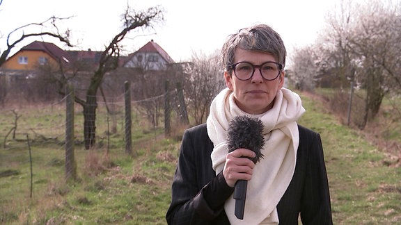 Reporterin Sandra Voigtmann mit Schal und Mikrofon