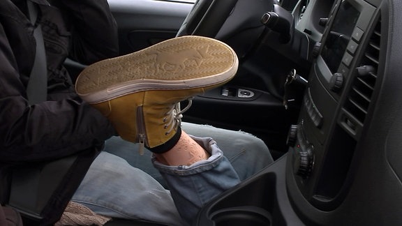 Beinprothese im Auto neben einem Lenkrad
