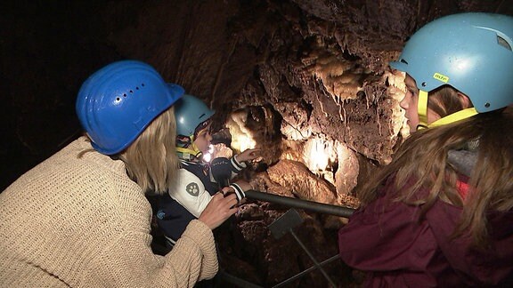 Kinder mit Reporterin in einer Höhle