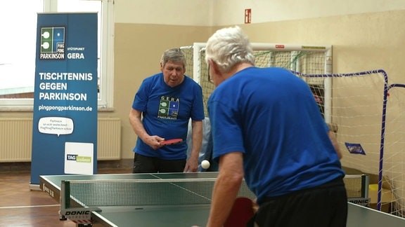 Zwei Männer stehen an einer Tischtennisplatte