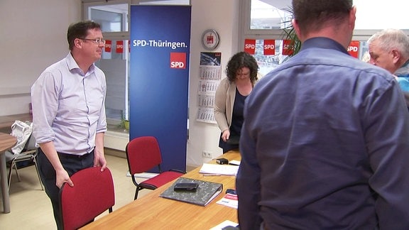 Mehrere Menschen stehen um einen Tisch, im Hintergrund ein Aufsteller mit dem Schriftzug "SPD-Thüringen"