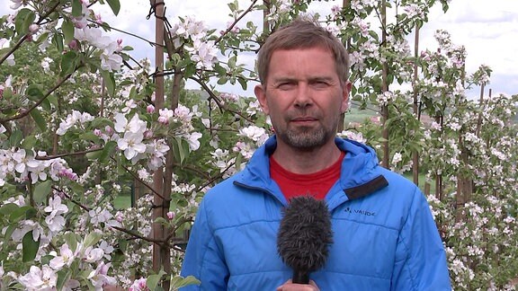 Wettermoderator Jens Roder vor blühenden Kirschbäumen