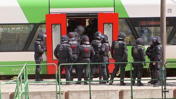 Einsatzkräfte der thüringer Polizei stehen während einer Übung an der Tür einer Regionalbahn.