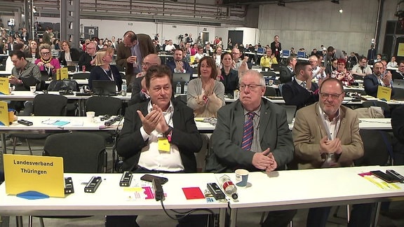 Drei Delegierte aus Thüringen hinter einem Tisch in der Parteitagshalle