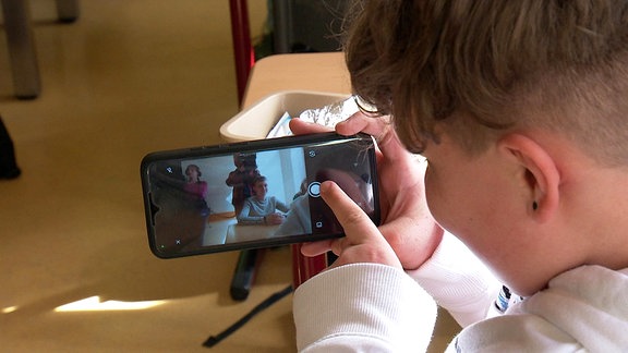 Ein Junge fotografiert mit seinem Handy