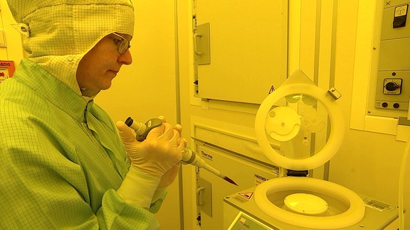 Eine Wissenschaftlerin in Schutzkleidung in einem Labor mit einer großen Pipette in der Hand