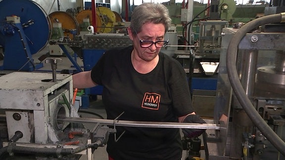 Eine Frau steht an einer Maschine in einer Werkhalle
