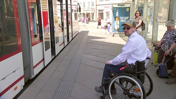 Ein Rollstuhlfahrer neben der Straßenbahn