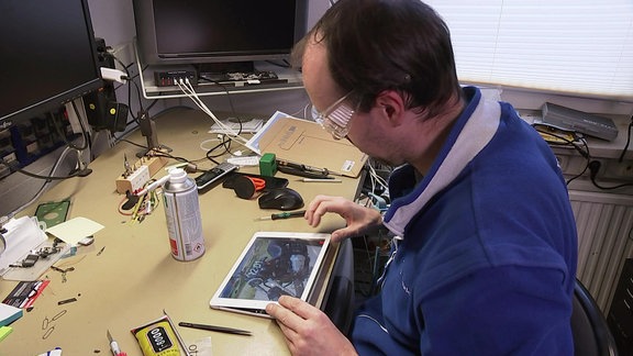 Ein Techniker repariert ein Tablet.