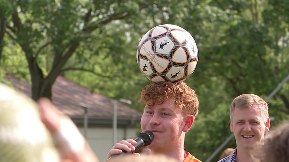 Mann mit Fußball auf dem Kopf