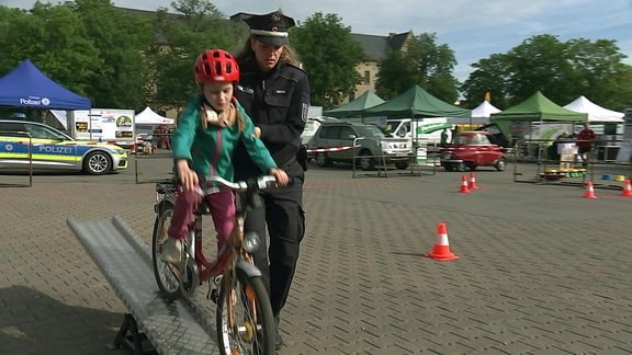 Polizistin hilft Kind über Fahrrad-Wippe