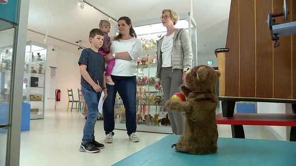 Eine Familie schaut sich im Museum eine Bären-Spielfigur an