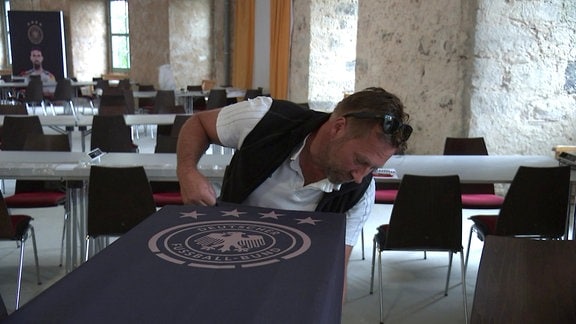 Ein Mann befestigt ein DFB-Banner in einer Gaststätte in Blankenhain