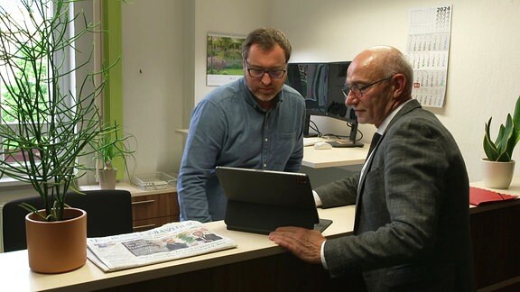 Der Landrat des Altenburger Landes  Uwe Melzer schaut mit einem weiteren Mann in einen Laptop