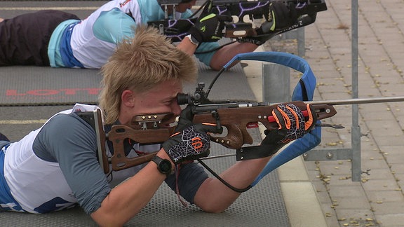 Ein junger Mann schießt im Liegen mit einem Biathlon-Gewehr
